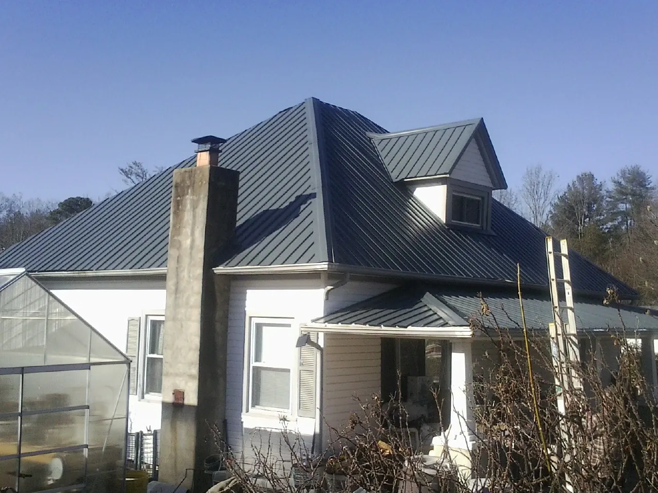Dark blue standing seam metal roof on a white farmhouse with dormer — Slate & Tile Roof Repair by Roofing Brothers in Commercial Point