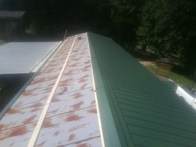 Old rusted panels beside newly installed green metal roofing — Wind Damage Roof Repair by Roofing Brothers in Commercial Point