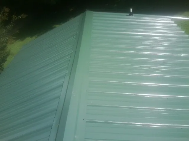 New green metal panels meeting at the ridge of a roof — Flat Roof Repair work by our crew in Commercial Point