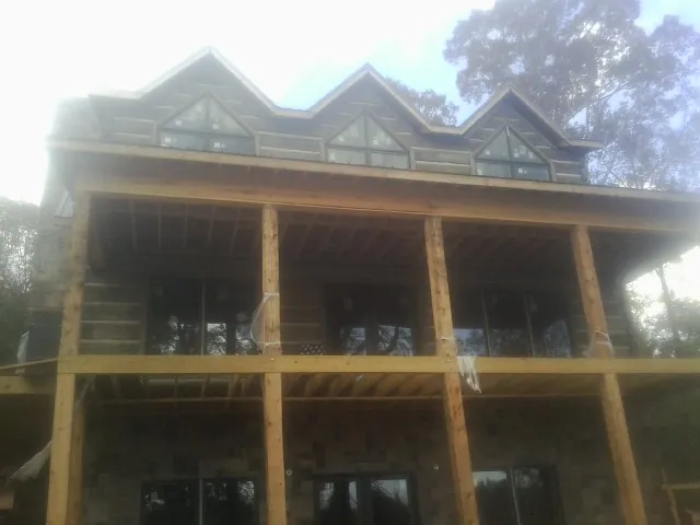 Dormers and porch framing on a large log home under construction — Roof Coating work by our crew in Commercial Point