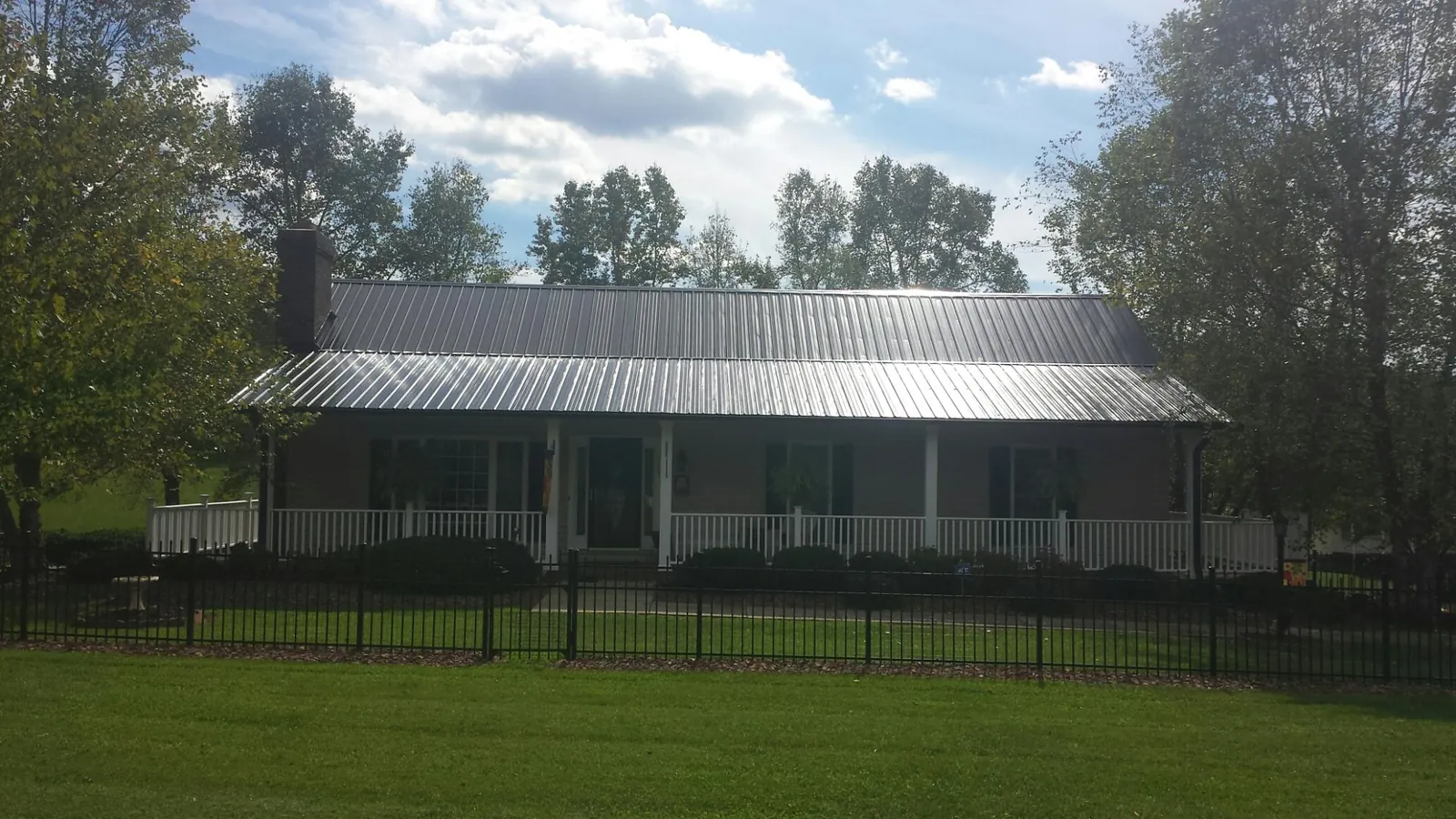 Gray metal roof on a brick ranch with a full width front porch — Gutter Guard Installation work by our crew in Commercial Point