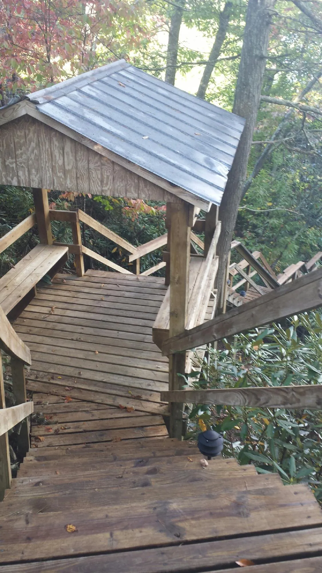 Metal roofed shelter over wooden steps on a wooded walkway — Skylight Repair & Installation work by our crew in Commercial Point