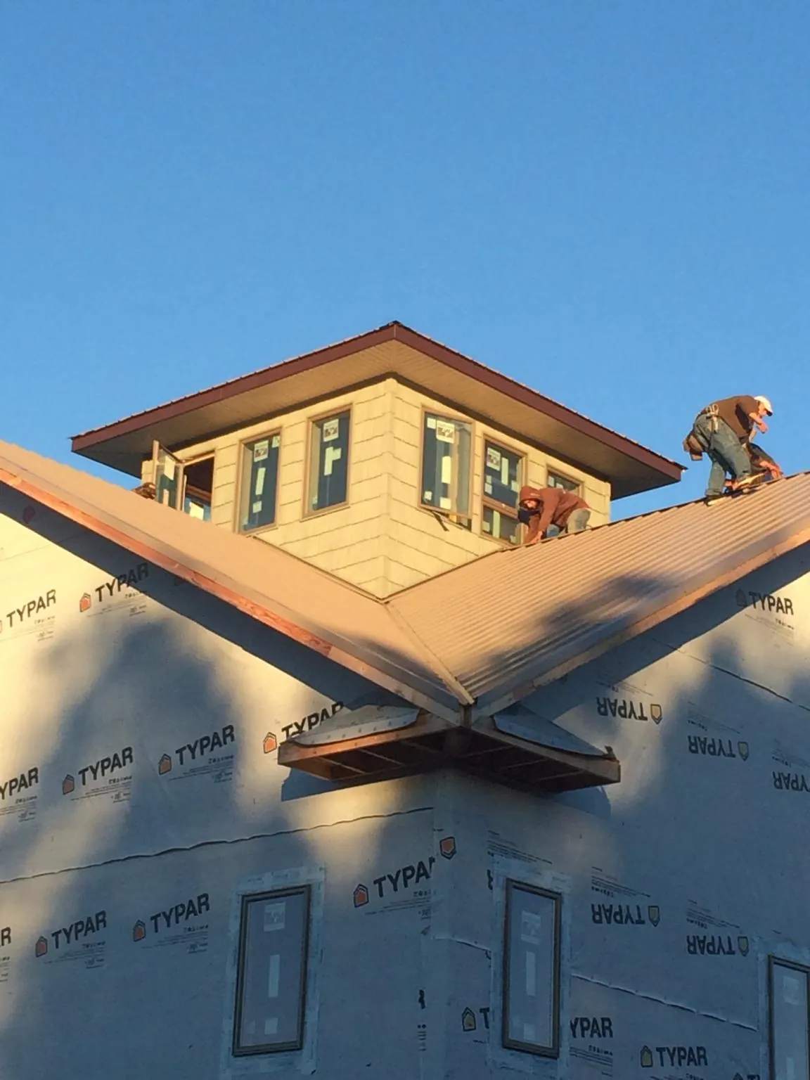 Roofers working around a rooftop cupola on a new metal roof at sunset — Roof Waterproofing in Commercial Point by Roofing Brothers